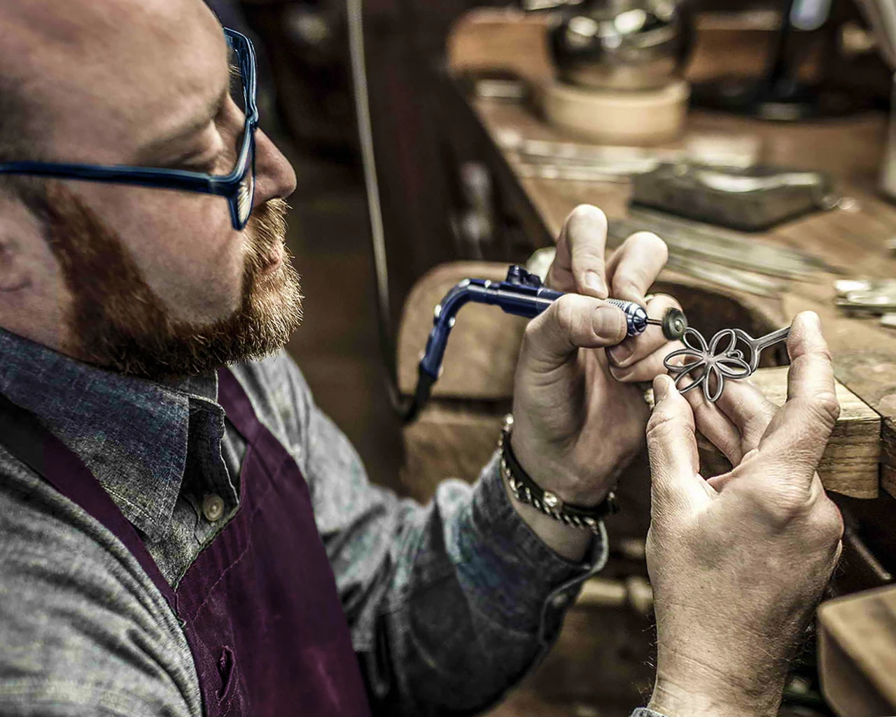 A jeweler at CJD Fine Jewelry is crafting a custom gold flower-shaped pendant. A jeweler at CJD Fine Jewelry is crafting a custom gold flower-shaped pendant.