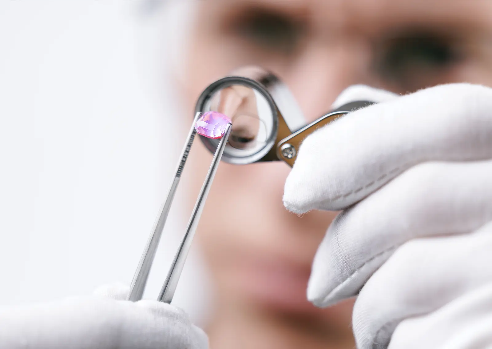 A gemologist examines a pink sapphire.