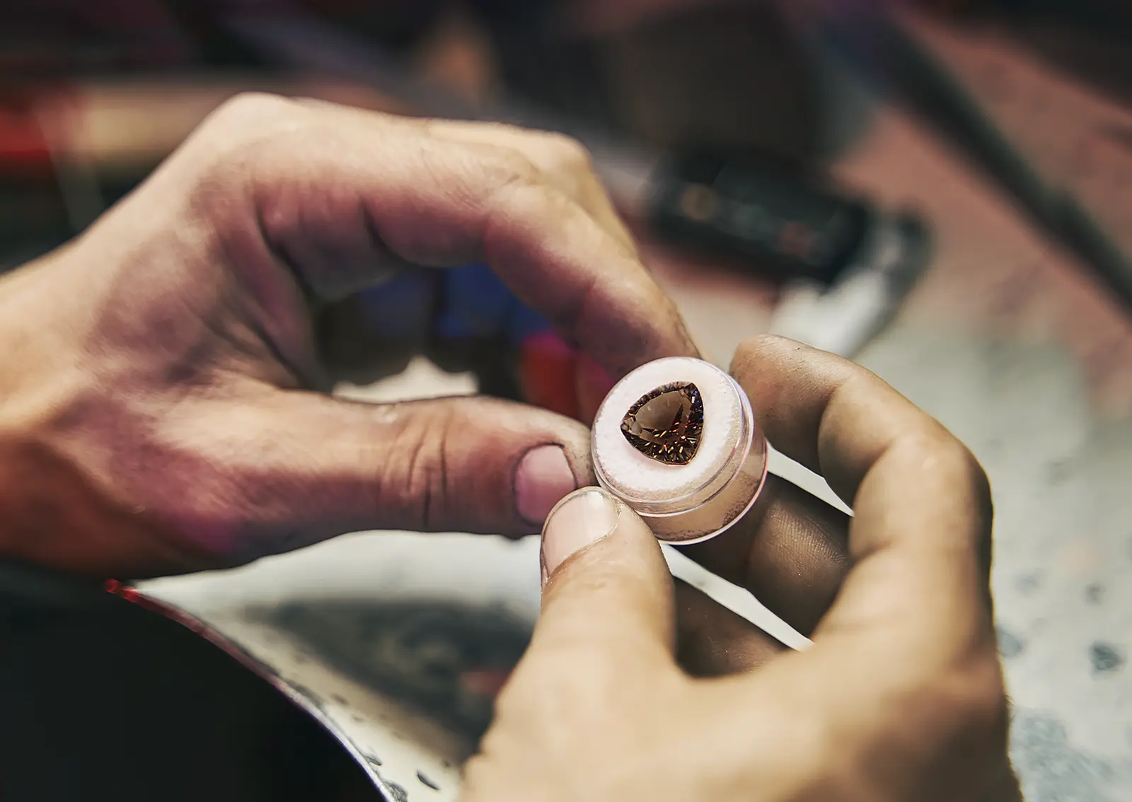 A jeweler examines a stone provided by a client. Can You Create Custom Jewelry Using My Own Stone, Heirloom, or Photo?