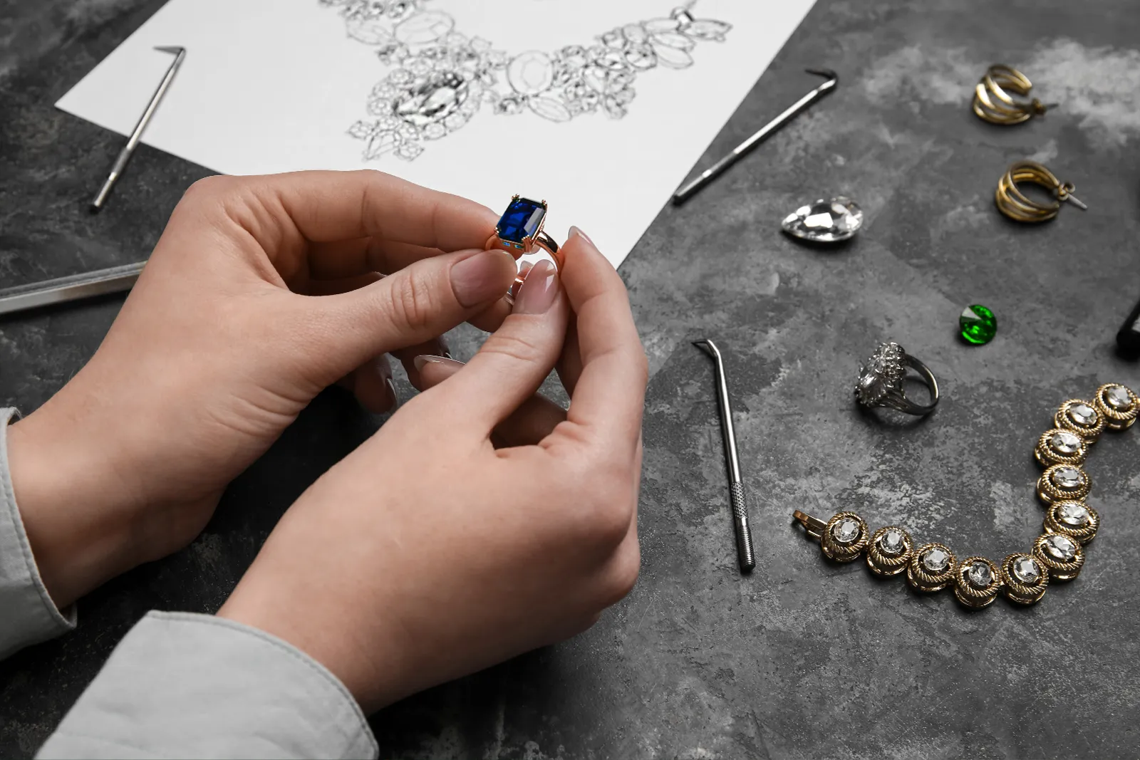 Jewelry designed at CJD Fine Jewelry stands out for its unique features. A ring with a stunning sapphire and a sketch of a necklace.